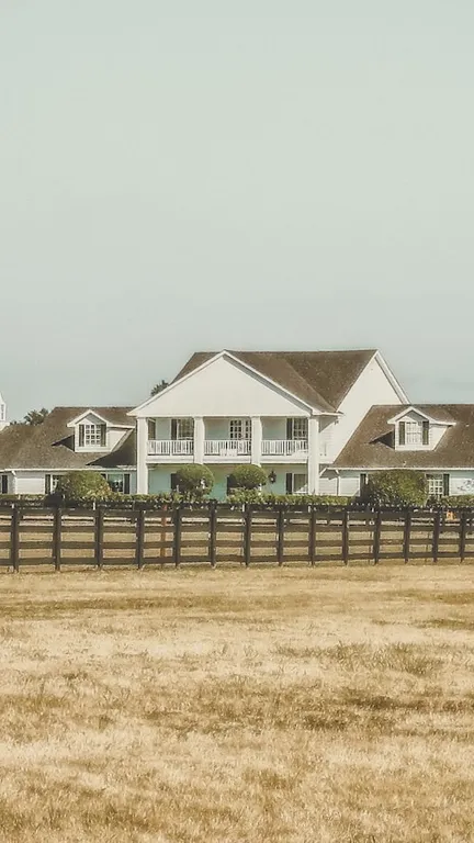 A white ranch-style estate behind a long fence in the Texas countryside, a representative single-family acquisition.